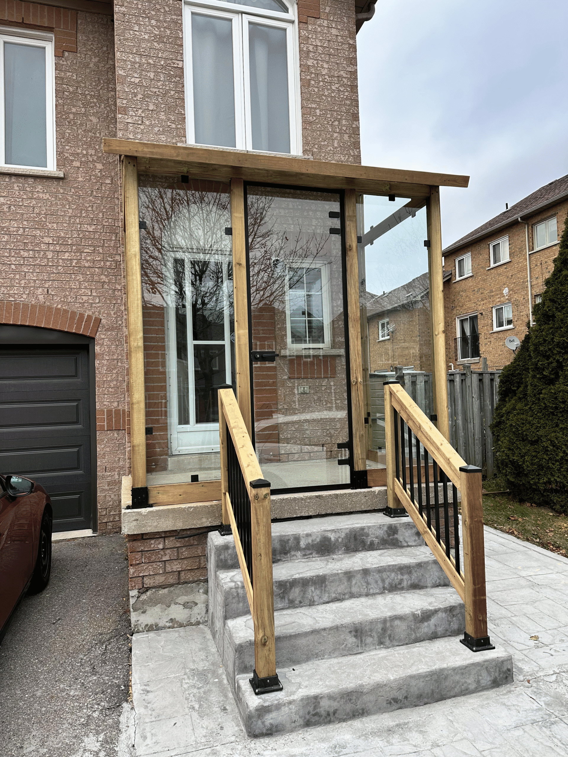 Exterior glass partition enclosing a front porch in Aurora built by Zelux Railings to provide weather protection and clear visibility while preserving natural light.