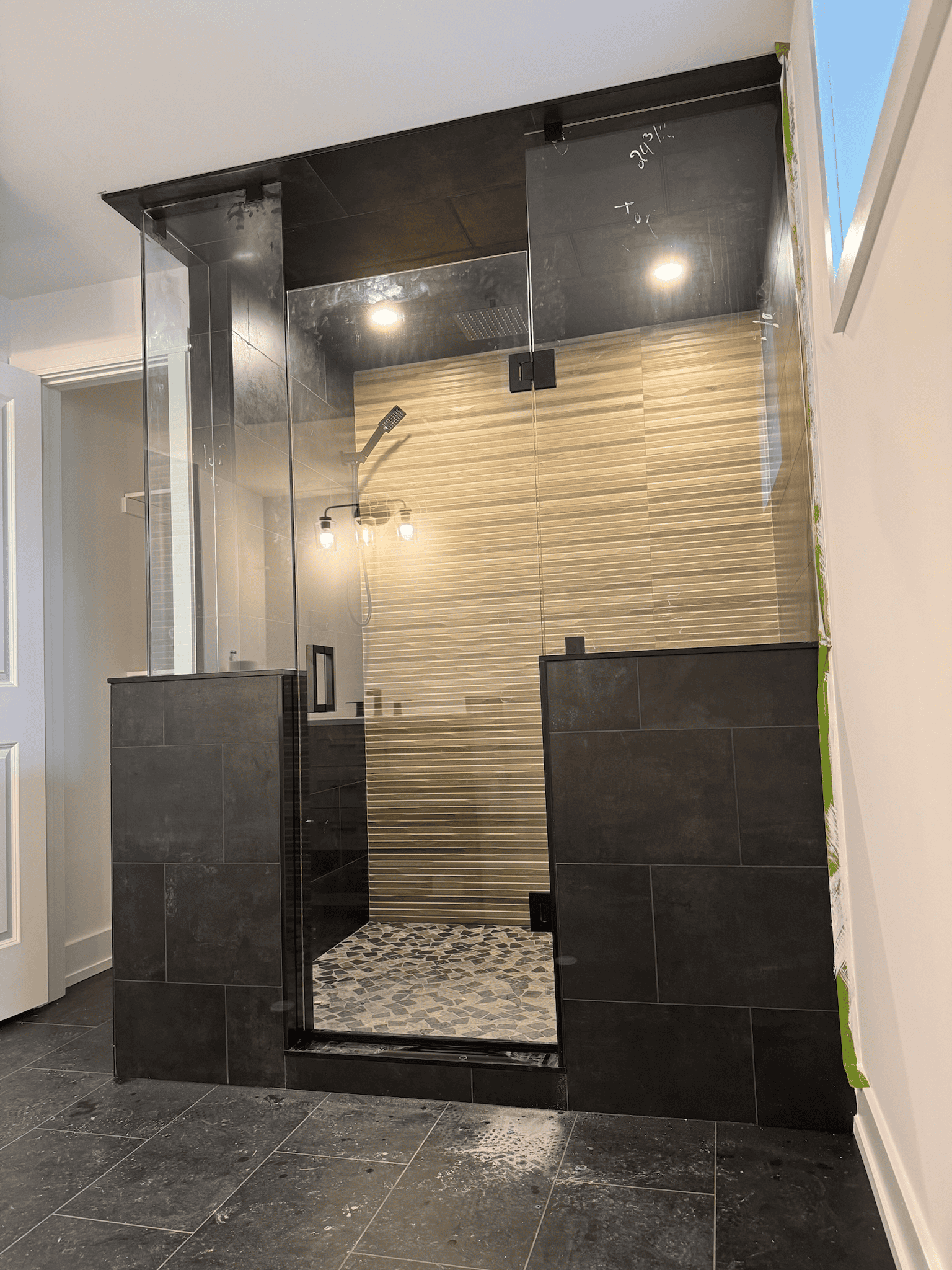 Frameless glass shower enclosure in Richmond Hill with dark tiles and wood-look walls — designed by Zelux Railings to bring modern elegance, natural light, and privacy together.