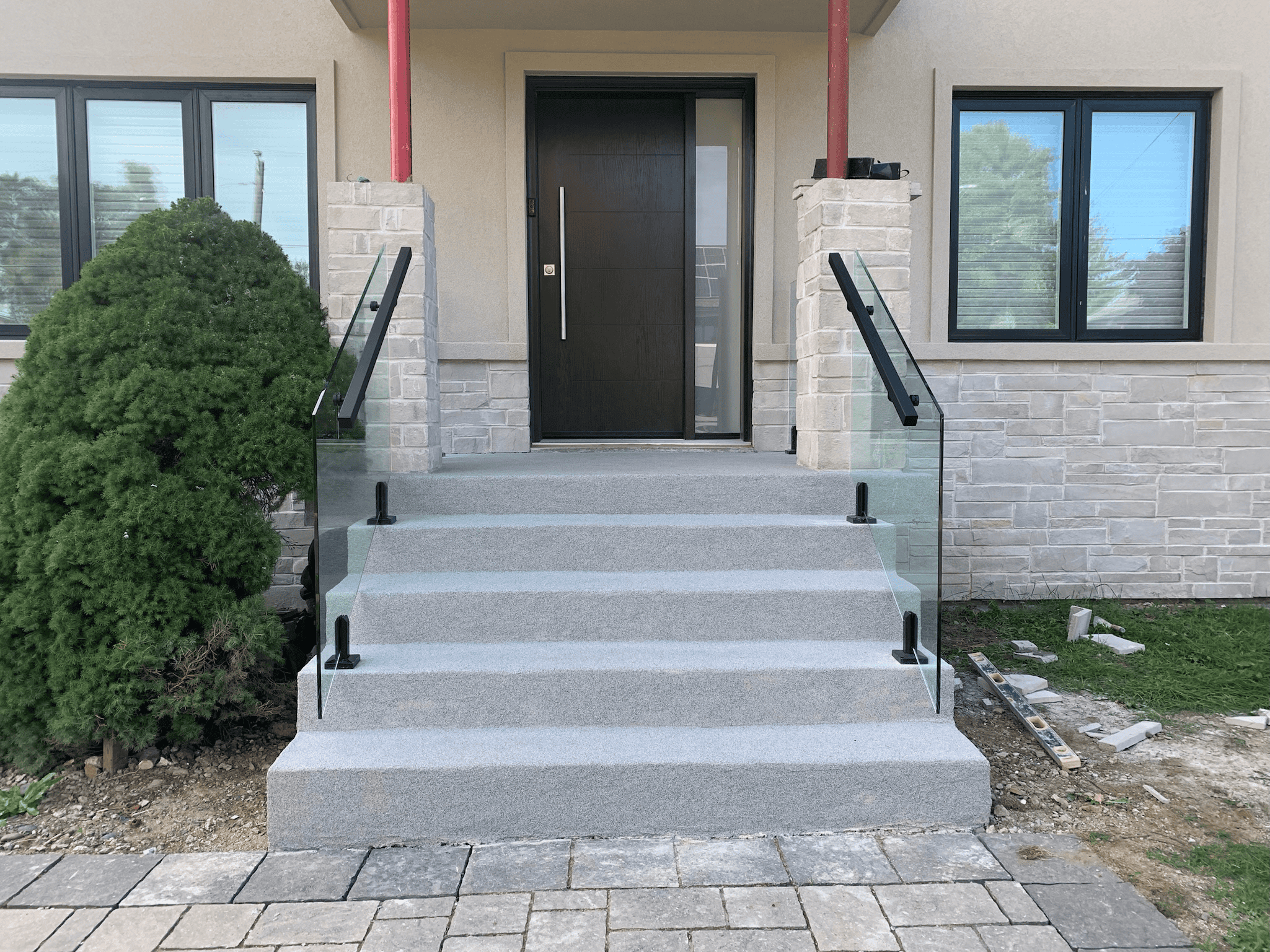 Custom glass stair railing installation for front steps by Zelux Railings in East Gwillimbury, Ontario – modern, frameless glass design with black handrails.